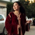 Joyful young woman wearing a velvet kaftan outdoors, exuding style and elegance.