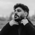 Monochromatic portrait of a man adjusting scarf, outdoors in Baku, Azerbaijan.